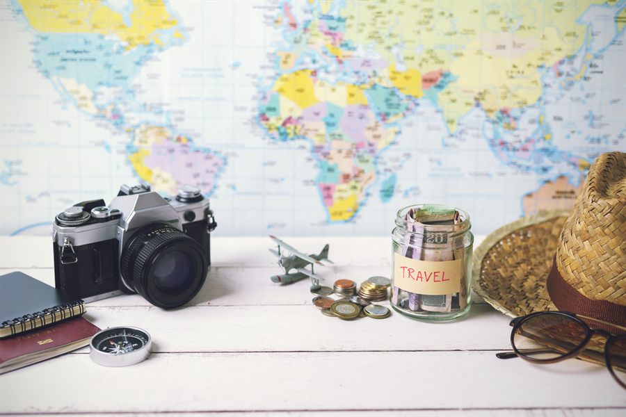 World map on a table with a camera, compass and travel notes for planning a river cruise budget